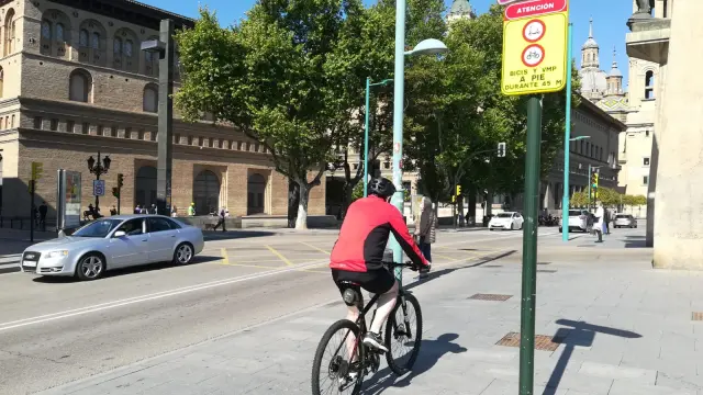 Un ciclista, este viernes, a su paso por la nueva señal que obliga a transitar a pie por el cruce del puente de Piedra.