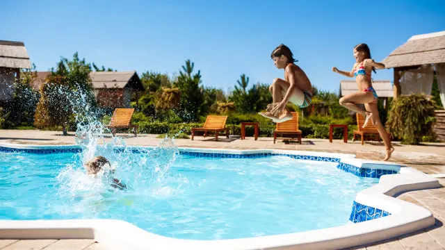 Cheerful children rejoicing, jumping, swimming in pool. Copy space