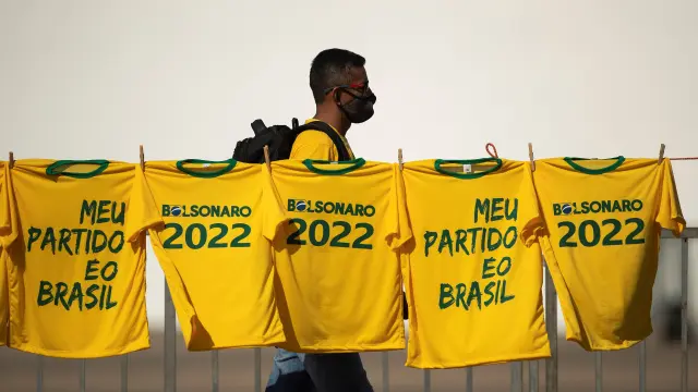 Un hombre camina junto a varias camisetas con lemas de apoyo a Bolsonaro