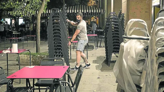Un camarero recoge una terraza de bar en la plaza de San Francisco de Zaragoza.