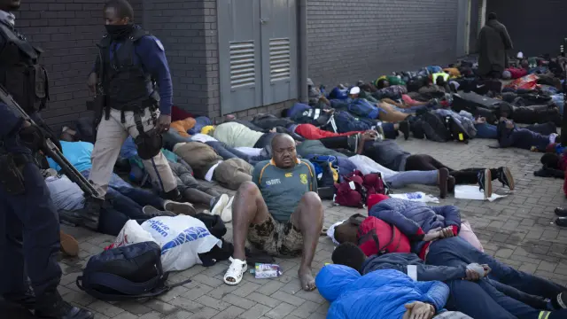 Decenas de personas tendidas en el suelo bajo arresto en Sudáfrica