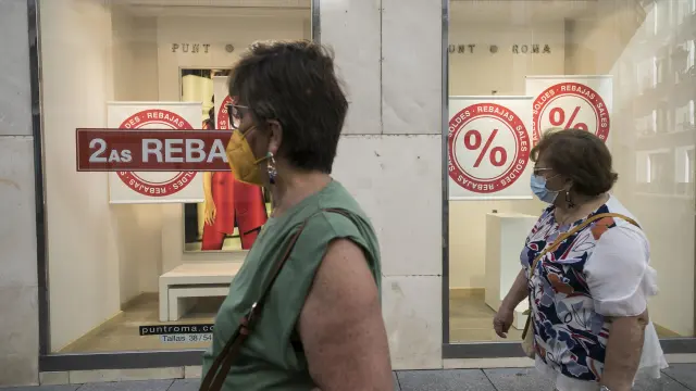 Dos mujeres pasean frente a un escaparate que anuncia las rebajas, en Zaragoza.
