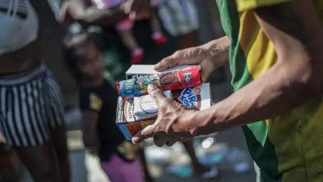 Un hombre recibe alimentos por parte de voluntarios de la eoenegé Covid Sem Fome en un barrio de Río de Janeiro, en Brasil.