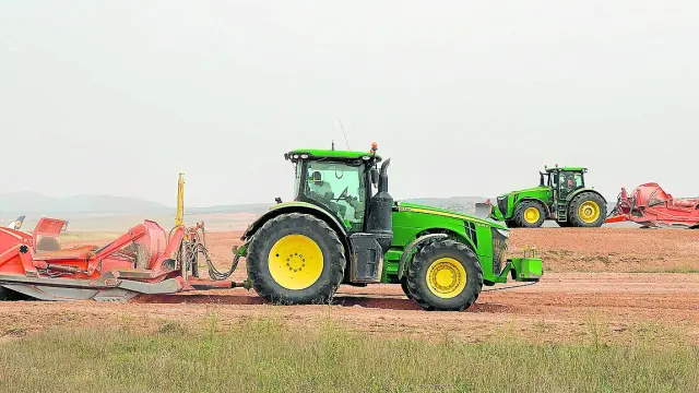Dos tractores retiran la cubierta de tierra fértil para nivelar el futuro aparcamiento del aeropuerto.