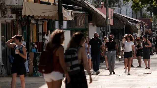 People walk along a street near a restaurant where, according to local media, two foreigners were killed and three injured during a shooting occurred between suspected gang members, in Tulum
