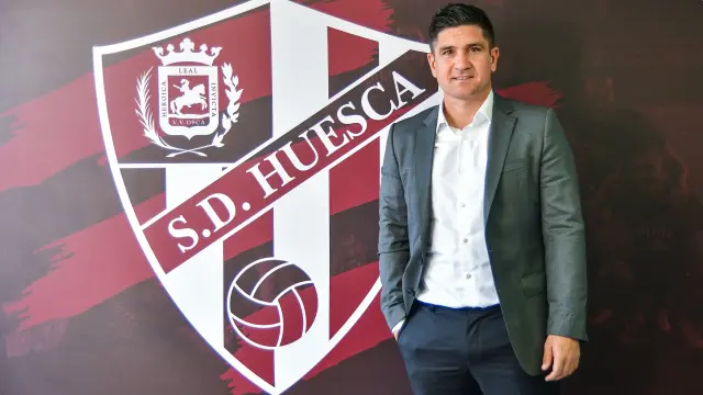 El técnico Xisco Muñoz posa junto al escudo de la SD Huesca.