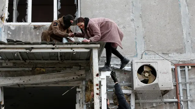 People take belongings out of a destroyed building in Mariupol