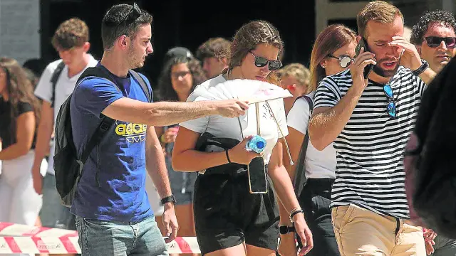 Un joven abanica a una chica mientras caminan por el centro de Zaragoza, ayer.