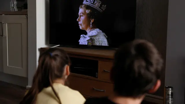 Unos niños ven el anuncio de la muerte de Isabel II en televisión.