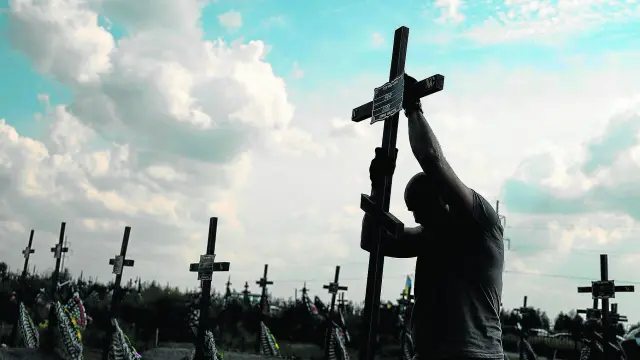 Un voluntario coloca el pasado agosto un cruz con un número en una tumba anónima entre enterramientos de asesinados por tropas rusas en Bucha