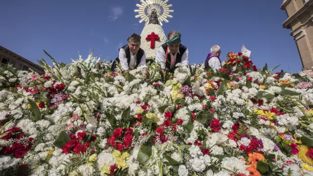 Jardineros colocando flores en el manto durante la Ofrenda de Flores en 2019