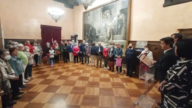 El alcalde se dirige a un grupo de visitantes en el salón del Justicia, con el célebre cuadro de La Campana de Huesca.