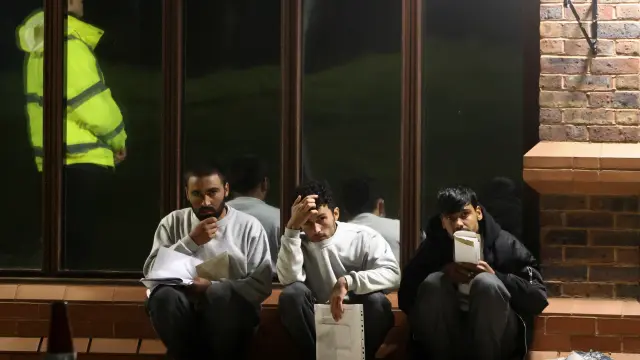 Tres migrantes afganos esperando a volver al centro de Manston, en Reino Unido.