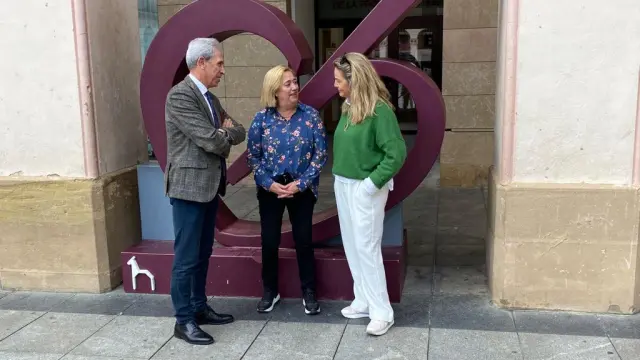 Salvador Cored, Rosa Gerbás y Susana Lacostena junto al logo del comercio de Huesca colocado delante de la sede de CEOS-Cepyme