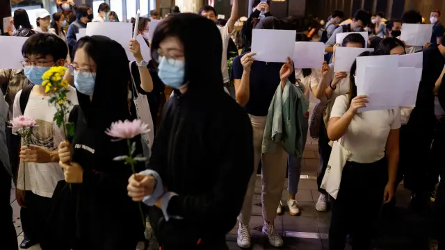 Los manifestantes sujetan folios blancos en protesta por las restricciones por la covid en China.