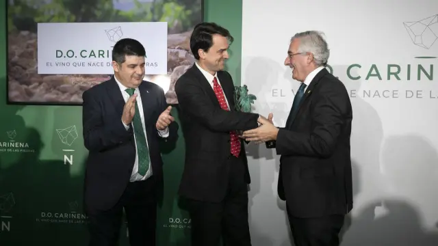 Joaquín Olona entrega el galardón a Christoph Wolfrum ante Antonio Ubide, en el 90 cumpleaños de la DO Cariñena en Madrid