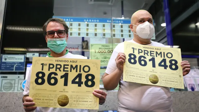 Dos trabajadores de la adminsitración de la estación de Atocha muestran el número del gordo.
