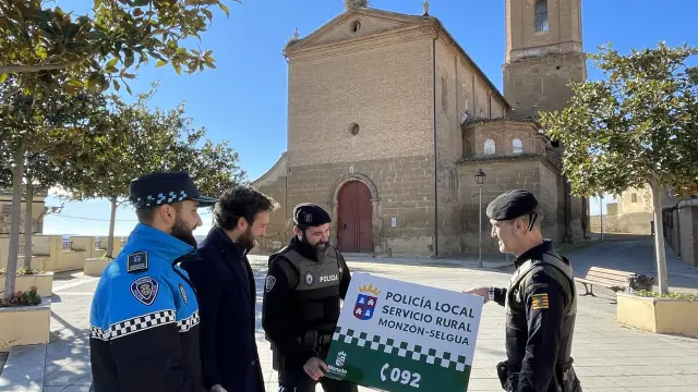 El alcalde de Monzón, Isaac Claver, con agentes de la Policía Local y de la Policía Rural con uno de los carteles indicativos de las nuevas oficinas
