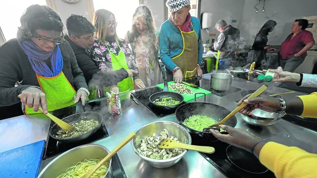 Las usuarias de Gambaru preparan la carbonara de champiñones y ajos para la pasta vegetal, en la cocina del Joaquín Roncal.