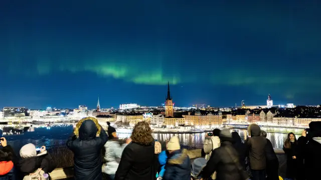 Varias personas contemplan las luces nocturnas de las autoras borales en Estocolmo (Suecia).