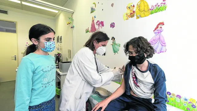 La enfermera Teresa Tolosana vacuna contra papiloma a Abel, junto a su hermana melliza, Ainhoa.