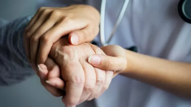 Personal sanitario agarra la mano de un anciano