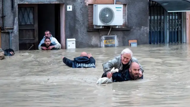 Dos carabinieri tratan de salvar a afectados por las inundaciones en la región de Emilia-Romaña, en Italia.