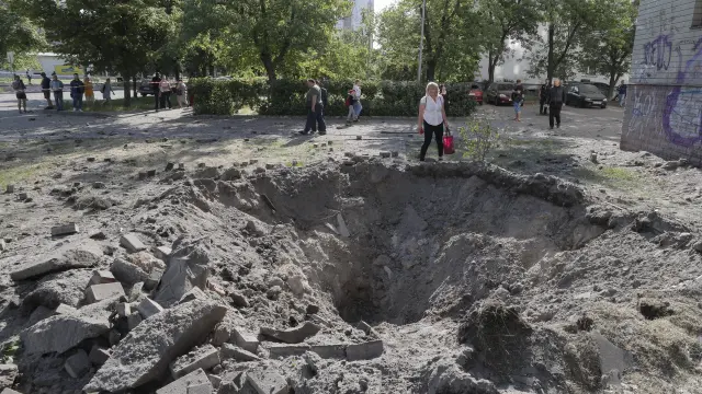 Una persona, junto a un cráter de proyectiles cerca de un edificio residencial tras un ataque con misiles en Kiev.