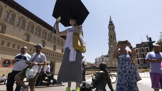 Primera ola de calor en Zaragoza. Gente con paraguas protegiéndose del sol en la plaza del Pilar.