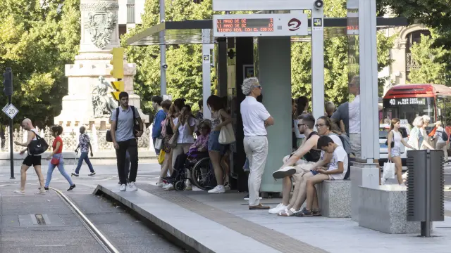 Varios usuarios esperan en una de las paradas del tranvía, en Zaragoza