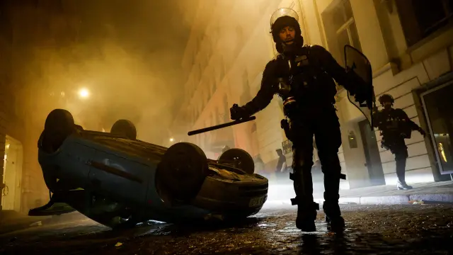 Policías antidisturbios franceses caminan junto a un vehículo durante el quinto día de protestas tras la muerte de Nahel
