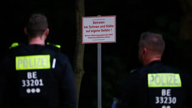 Police officers look at a sign as the search continues after police warned the public that a suspected lioness was on the loose, in Zehlendorf, Berlin, Germany July 20, 2023. The sign reads: "Enter at your own risk when it is snowy or icy". REUTERS/Annegret Hilse