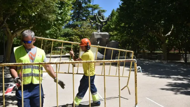 Dos operarios proceden a retirar las vallas instaladas en uno de los accesos principales, el del monumento a los Reyes de Aragón.