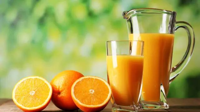 Una jarra y un vaso de zumo de naranja.