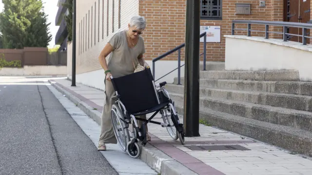 María Pilar Gimeno demuestra que la silla de ruedas no cabe por la acera.