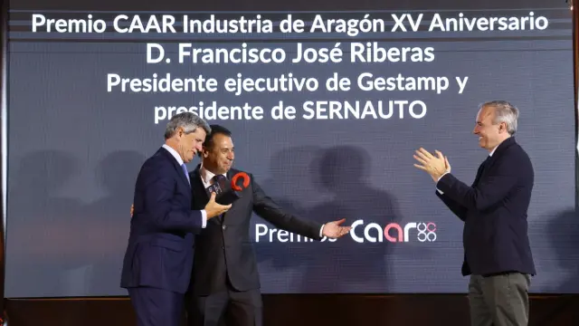 Francisco Riberas, presidente de Gestamp, recibe el premio XVaniversario del CAAR de manos del presidente del clúster aragonés, Benito Tesier. Frente a ellos, el presidente del Gobierno de Aragón, Jorge Azcón, aplaude al galardonado.