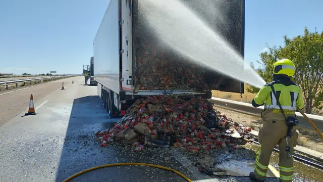 Los bomberos han arrojado al suelo parte de la carga del camión para poder sofocar las llamas con mayor rapidez.