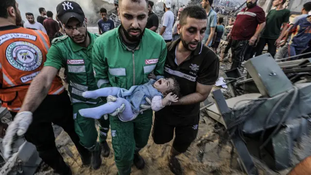 Los palestinos cargan a una niña herida después de recuperarla de los escombros de una zona destruida tras los ataques aéreos israelíes en la ciudad de Gaza