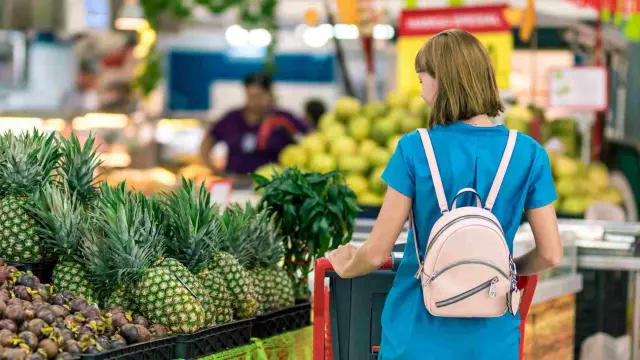 Una mujer comprando frutas en un supermercado.