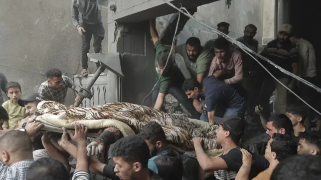 Varios palestinos rescatan un cadáver entre los escombros de un edificio