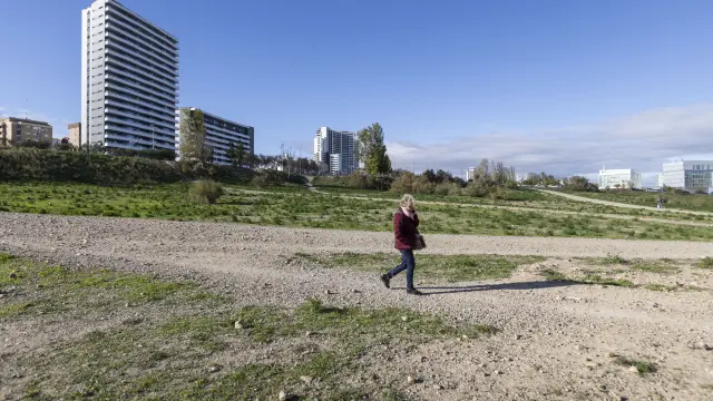 Una mujer pasea por los terrenos cercanos a la avenida de Ciudad de Soria, con dos torres de edificios al fondo.