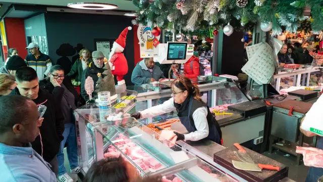 Varios clientes esperan su turno en una de las carnicerías del Mercado Central de Zaragoza