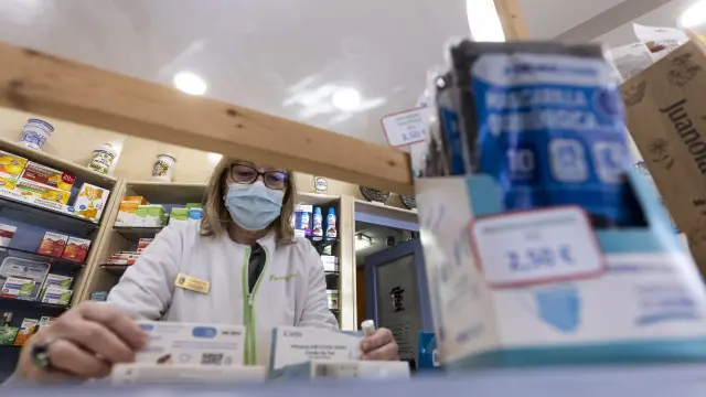 Pilar Labat, en la Farmacia Labat Casanova de Zaragoza, muestra unos test de antígenos y unas mascarillas.