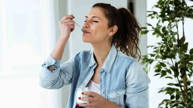 Una mujer comiendo un yogur.