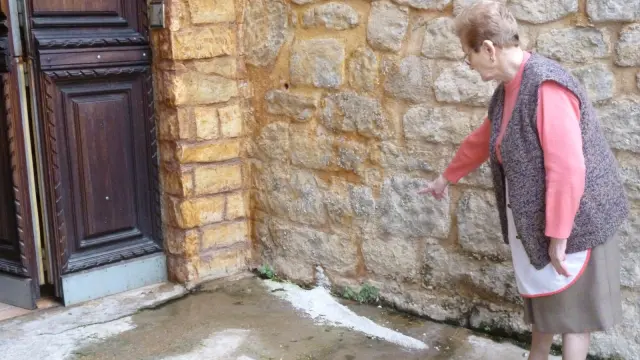 Pilar Lahuerta muestra las aguas fecales que afloran en la puerta de su casa.