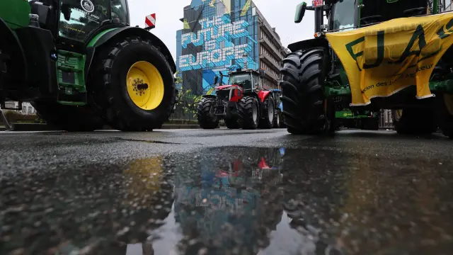 A farmer runs behind tires as he is sprayed by a water cannon during a protest of European farmers over price pressures, taxes and green regulation, on the day of an EU Agriculture Ministers meeting in Brussels, Belgium February 26, 2024. REUTERS/Yves Herman [[[REUTERS VOCENTO]]] EUROPE-FARMERS/PROTEST-BELGIUM