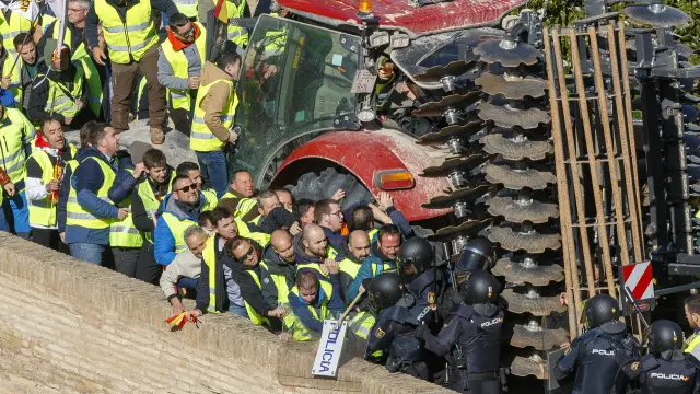 ZARAGOZA, 01/03/2024.- Un grupo de agricultores intenta romper el cordón policial mientras se concentran en los alrededores del Palacio de La Aljafería, sede de las Cortes de Aragón, este viernes en Zaragoza. EFE/ Javier Belver