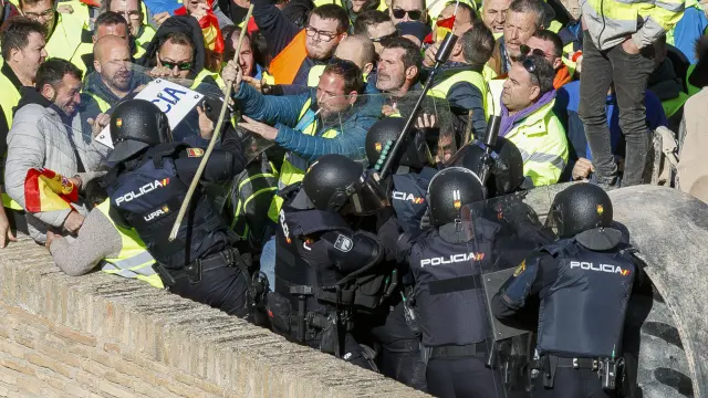 ZARAGOZA, 01/03/2024.- Un grupo de agricultores intenta romper el cordón policial mientras se concentran en los alrededores del Palacio de La Aljafería, sede de las Cortes de Aragón, este viernes en Zaragoza. EFE/ Javier Belver