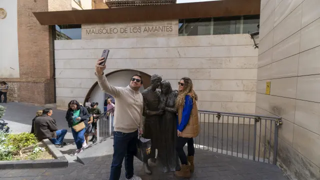 Una pareja de turistas, junto a la estatua de Los Amantes de Teruel.