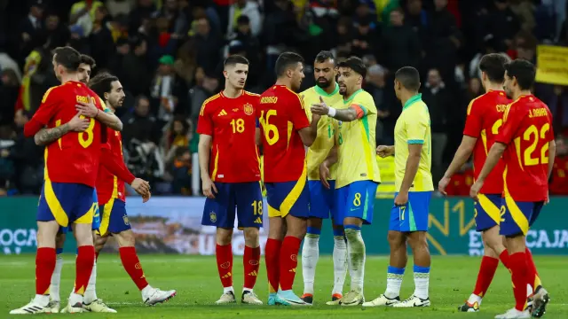 El centrocampista de la selección brasileña Lucas Paquetá (c-d) habla con Rodri, de España, durante el partido amistoso que las selecciones nacionales de fútbol de España y Brasil disputan hoy martes en el estadio Santiago Bernabéu, en Madrid.
